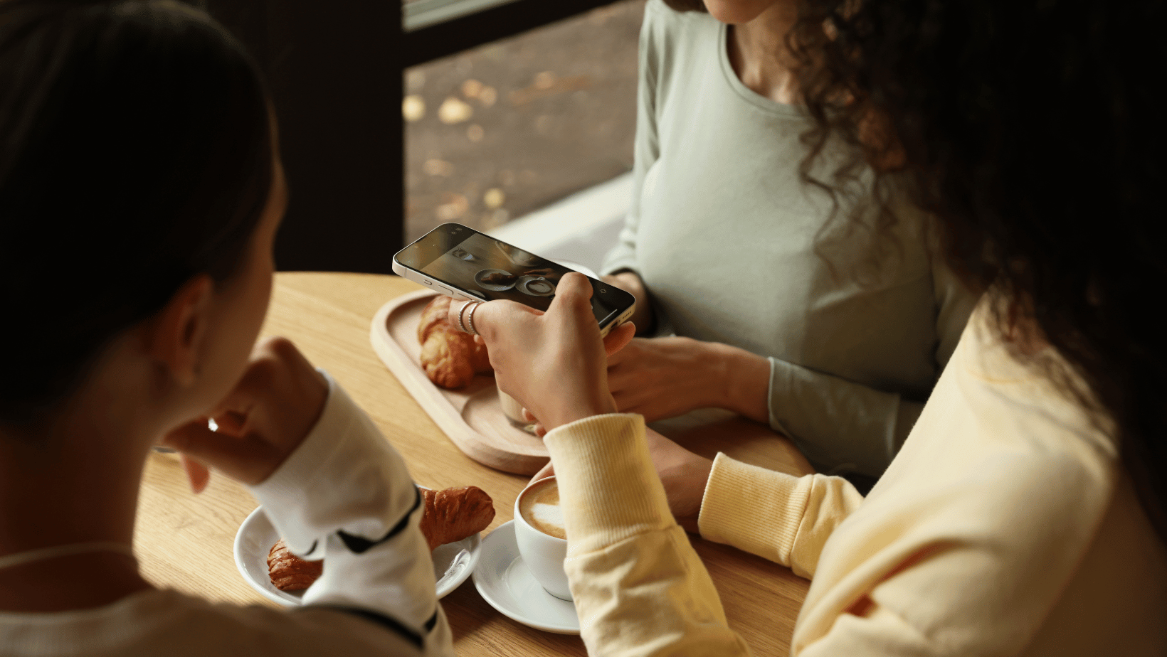 friends taking an instagram photo in a coffee shop
