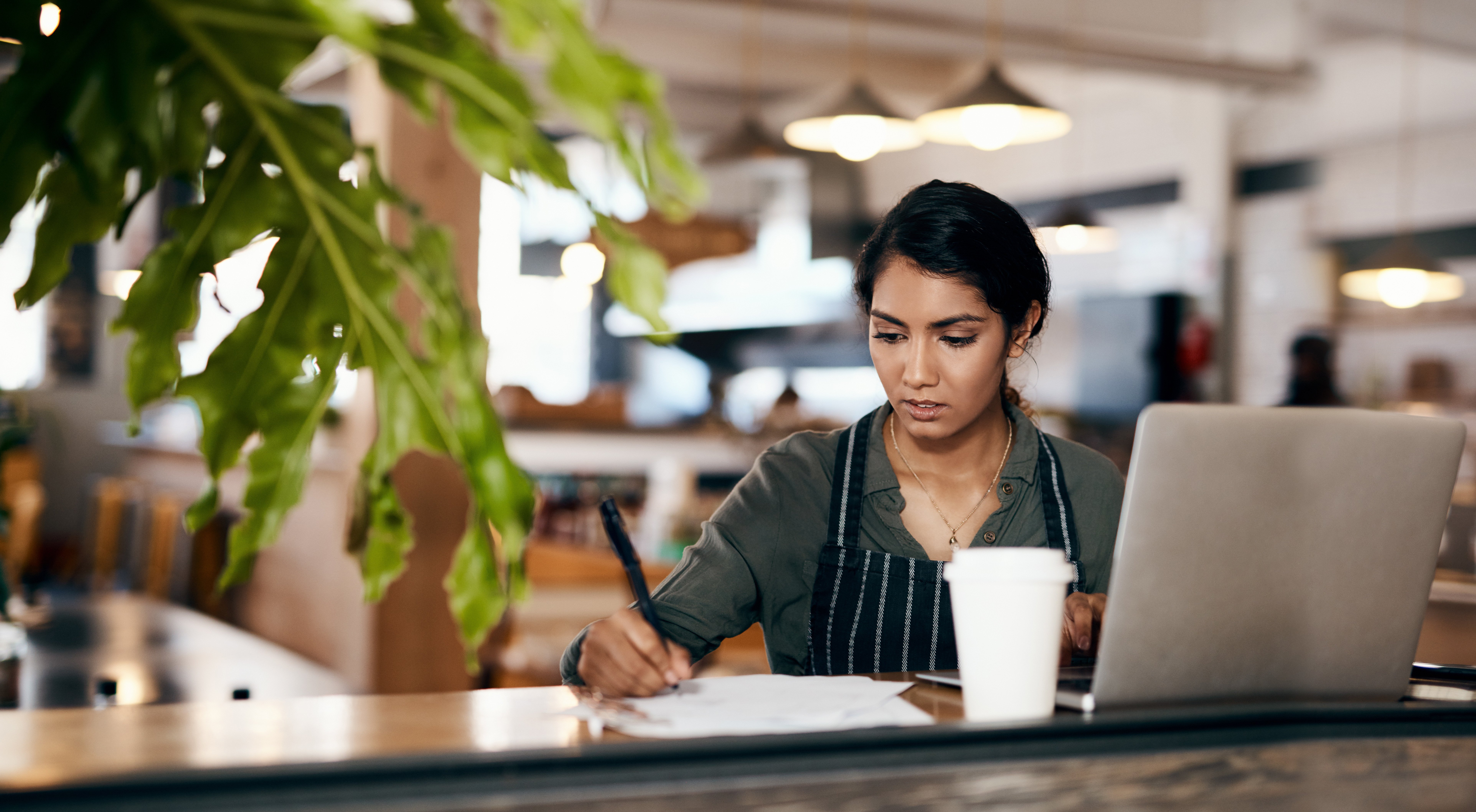 woman planning out her profit margins at a coffee shop