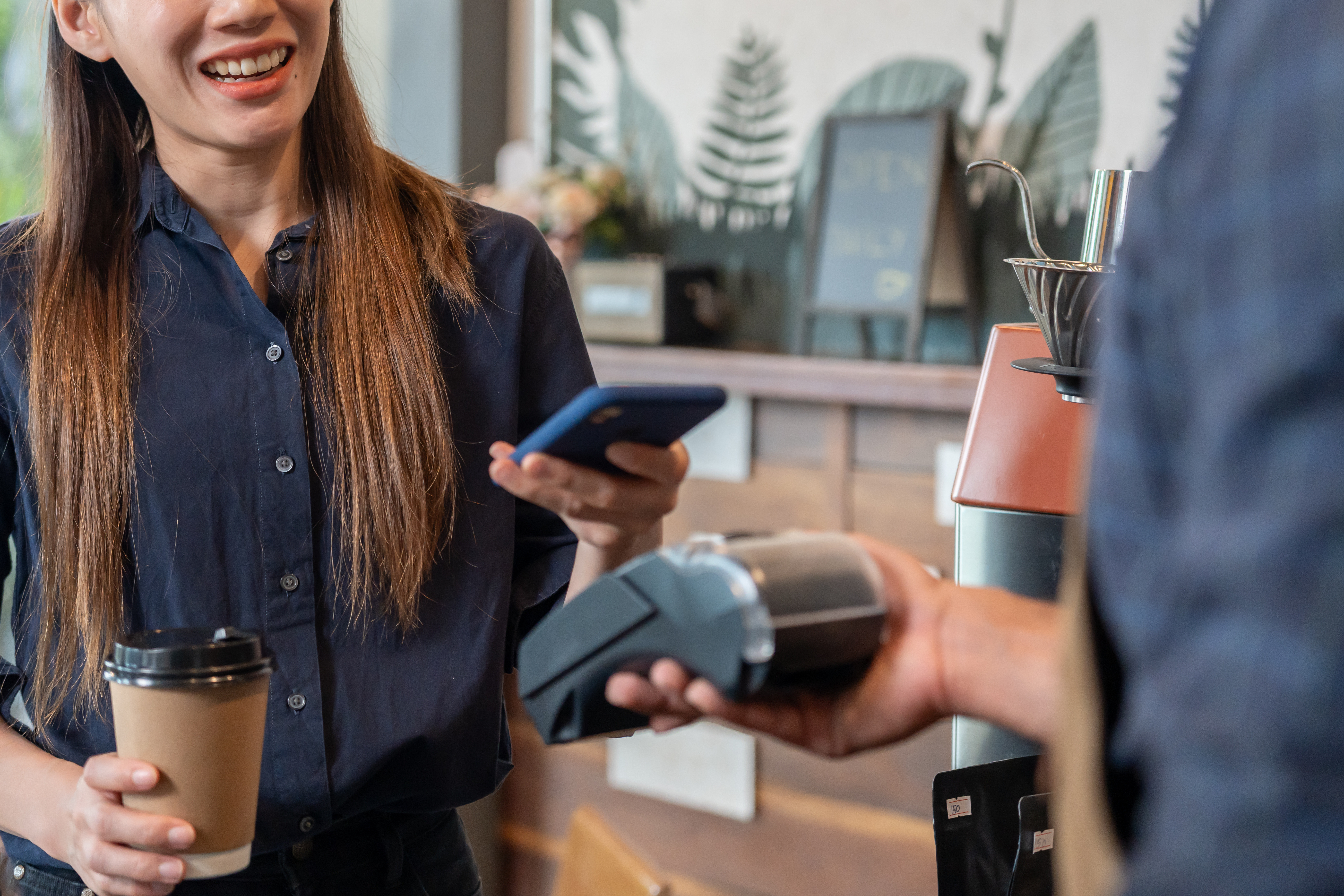 Woman purchasing a coffee at a coffee shop using Apple Pay 